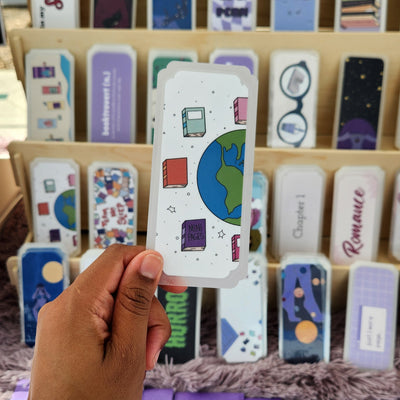 Hand holding a colorful card with a wooden board displaying various cards in the background.